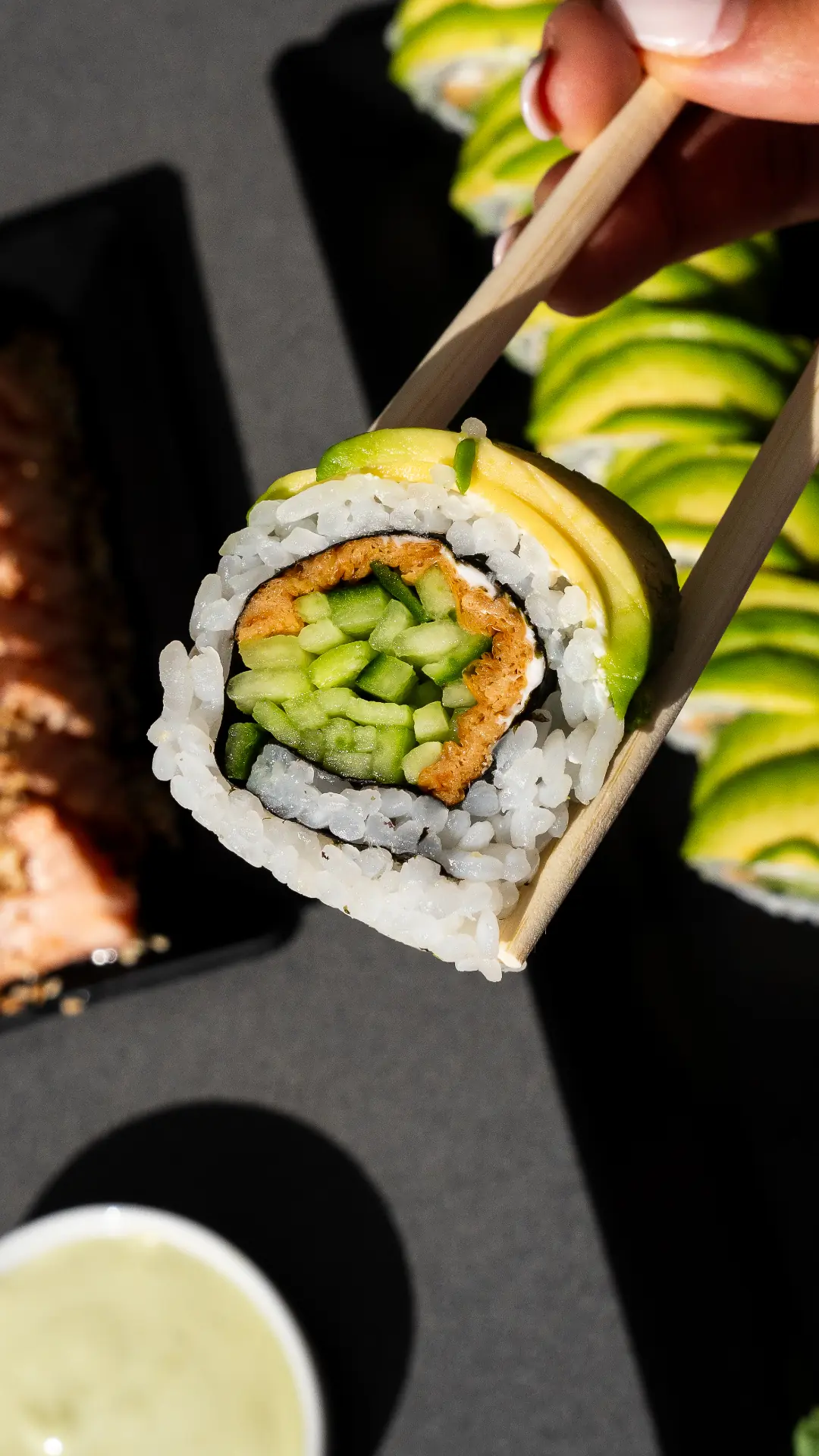 Sushi z awokado trzymane pałeczkami